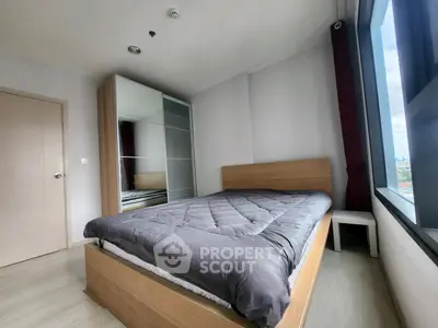 Modern bedroom with large window and sleek wooden furniture in a high-rise apartment.
