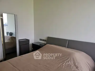 Modern bedroom with sleek design and neutral tones, featuring a stylish bed and mirror.