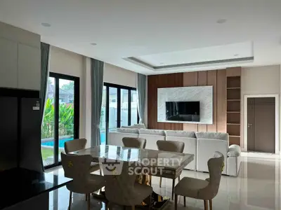 Luxurious living room with elegant dining area and pool view, featuring modern decor and ample natural light.
