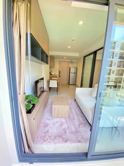 Modern living room with open layout and balcony view, featuring stylish furniture and natural light.