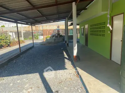 Spacious outdoor area with covered patio and green exterior walls, perfect for relaxation and gatherings.