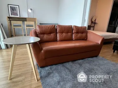 Spacious living room with modern furniture, featuring a luxurious leather sofa, cozy grey rug, and sleek coffee table.