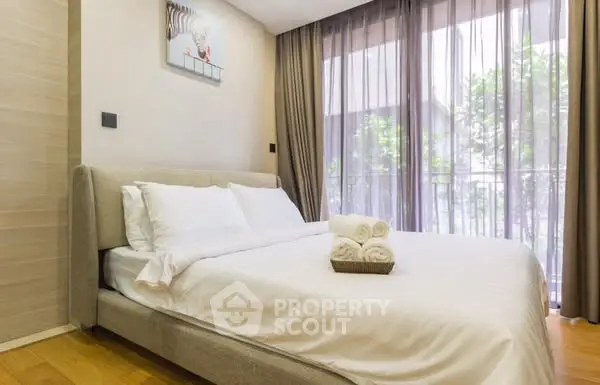 Elegant bedroom with cozy bed and floor-to-ceiling windows overlooking lush greenery.
