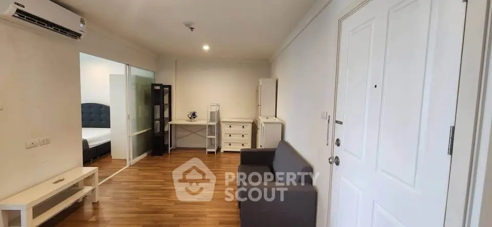 Spacious living room with wooden flooring and modern furniture in a cozy apartment.