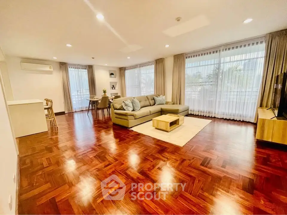Spacious living room with elegant wooden flooring and large windows for natural light.