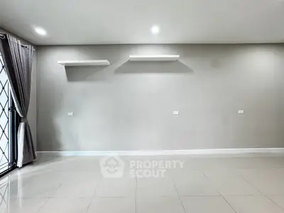 Spacious empty room with tiled floor and wall-mounted shelves, ready for customization.