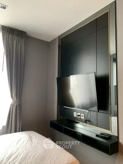 Modern bedroom with wall-mounted TV and elegant curtains