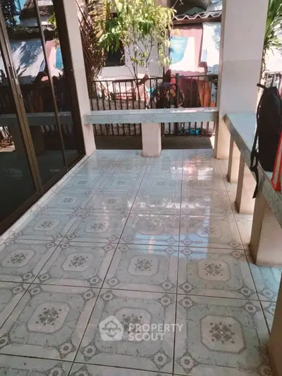 Charming tiled balcony with natural light and garden view, perfect for relaxation.