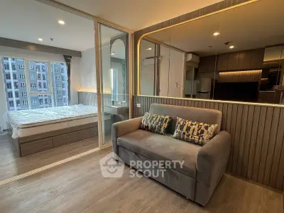 Modern apartment interior with cozy living room and stylish bedroom separated by glass partition.