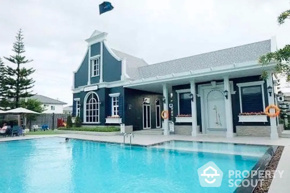 Charming blue and white themed house with a spacious outdoor swimming pool, surrounded by lush greenery and a serene environment, perfect for luxurious living.