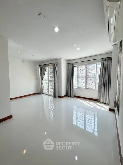 Spacious and bright living room with large windows and elegant curtains