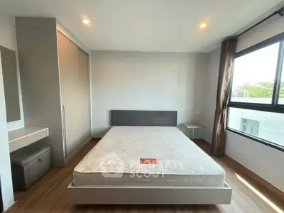 Spacious bedroom with large window and modern furnishings in a bright apartment.