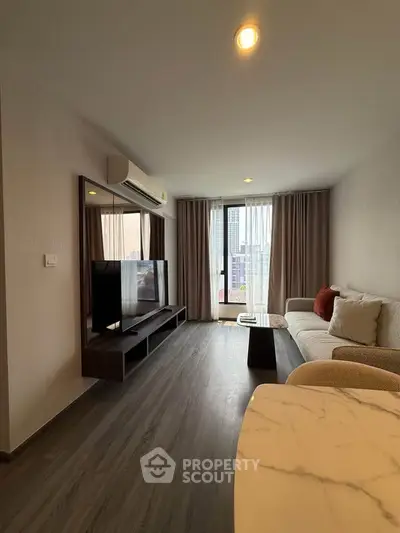 Modern living room with stylish decor and city view, featuring a cozy sofa and large TV.