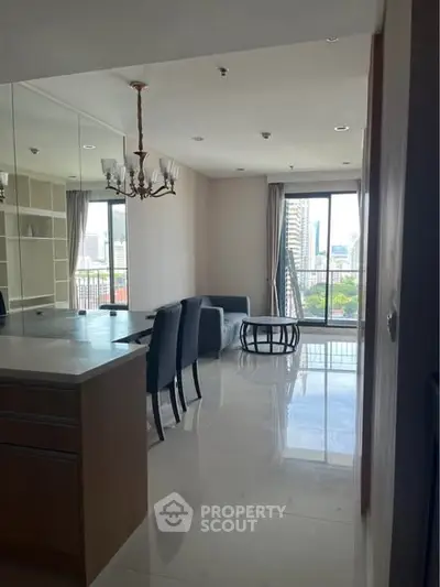Spacious modern living room with elegant chandelier and city view, perfect for urban living.