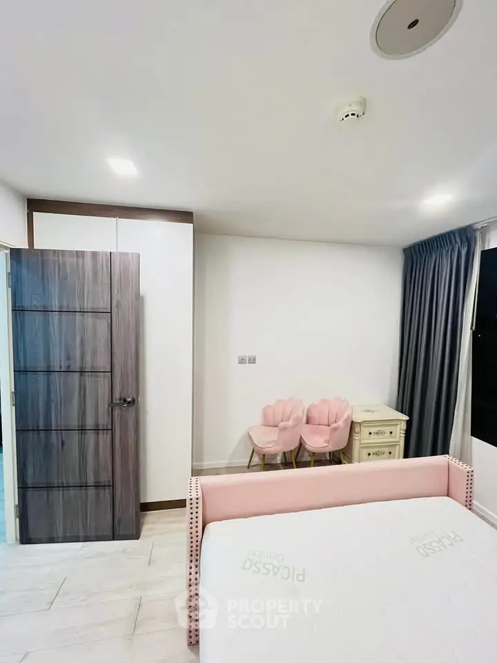 Charming bedroom with modern decor, featuring a cozy bed, stylish chairs, and ample storage space.