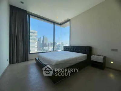 Spacious bedroom with stunning city view and modern furnishings in high-rise apartment.