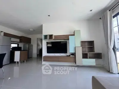 Spacious modern living room with sleek furniture and large TV, perfect for relaxation and entertainment.