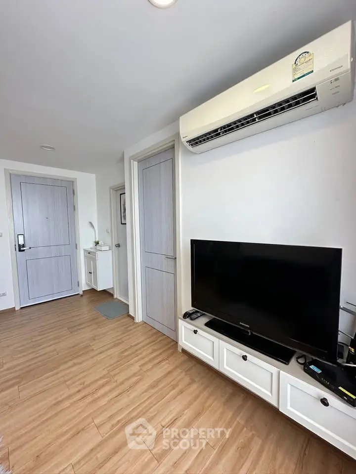 Modern living room with wooden flooring, air conditioning, and sleek TV setup.