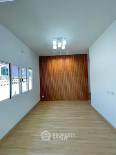 Spacious modern room with wooden accent wall and large windows for natural light.