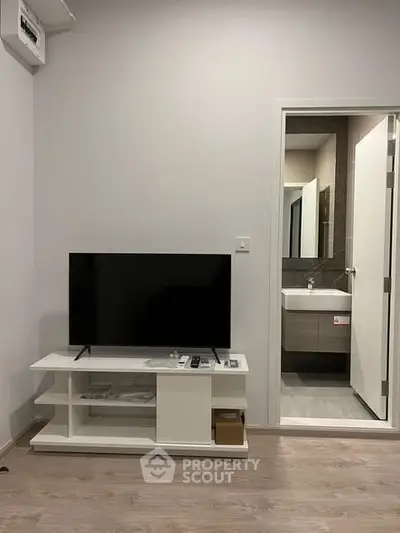 Modern living room with sleek TV stand and view into stylish bathroom