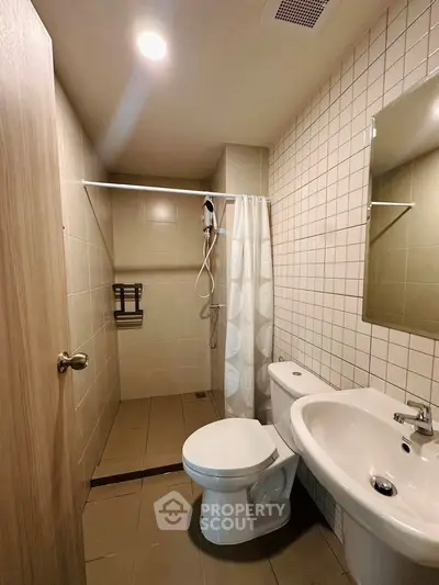 Modern bathroom with shower, toilet, and sink in a tiled setting