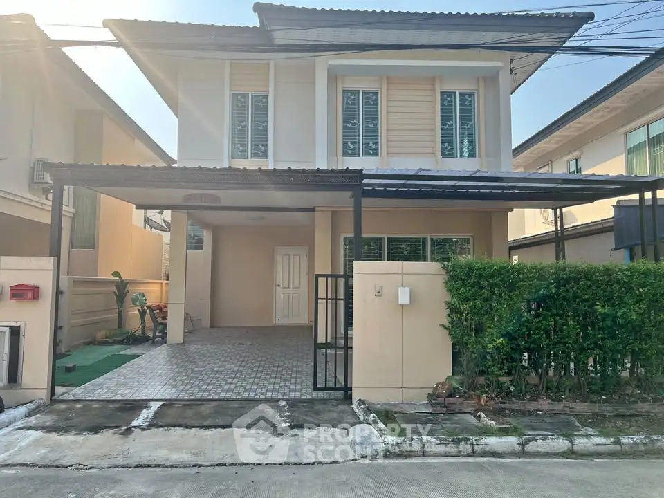 Charming two-story house with carport and lush greenery in a serene neighborhood.