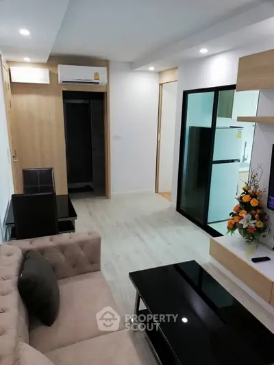 Modern living room with stylish furniture and open layout, featuring a sleek kitchen area and elegant decor.