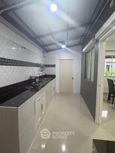 Modern kitchen with sleek black and white design, featuring open layout and ample counter space.