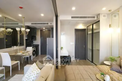 Modern open-plan living room and bedroom with elegant decor and dining area, featuring a washing machine and stylish lighting.
