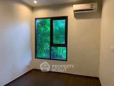 Bright room with large window and air conditioning, overlooking lush greenery.