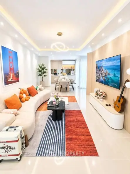 Modern living room with stylish decor and open layout, featuring a cozy seating area and large TV.