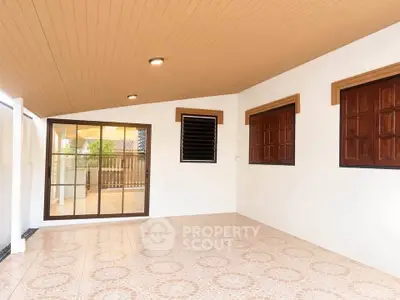 Spacious covered patio with elegant tile flooring and wooden accents, perfect for outdoor relaxation.