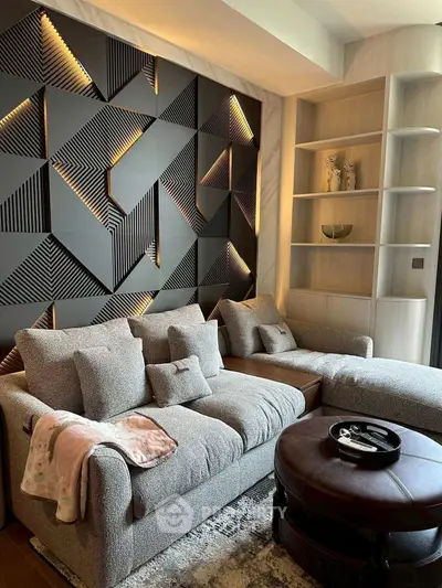 Modern living room with stylish geometric wall design and cozy gray sofa