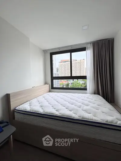 Modern bedroom with large window and city view, featuring a comfortable bed and minimalist decor.