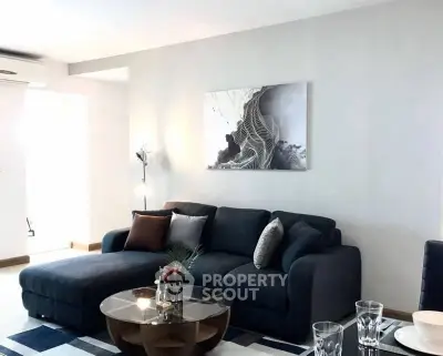 Modern living room with stylish dark sofa and abstract wall art, perfect for relaxation and entertaining.