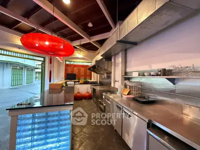 Spacious commercial kitchen with modern stainless steel appliances and vibrant red lighting.