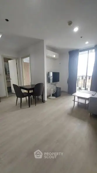 Spacious modern living room with dining area and balcony access in a bright apartment.