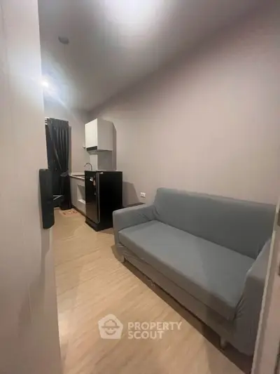 Cozy small living room with gray sofa and compact kitchen area