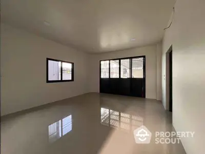 Spacious empty room with large windows and glossy tiled floor