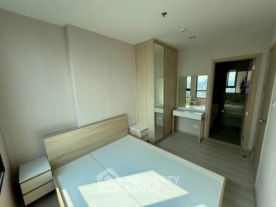 Modern bedroom with ensuite bathroom and wooden furniture in a bright apartment.
