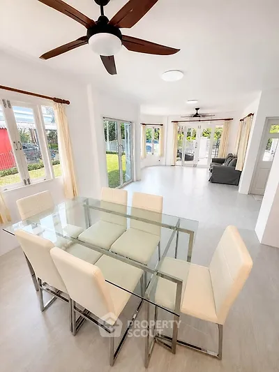 Spacious modern living and dining area with glass table and garden view