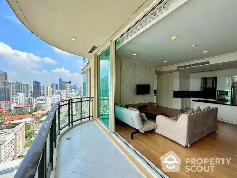 Luxurious high-rise condo with expansive balcony offering panoramic city views, featuring a spacious living area with modern furnishings and floor-to-ceiling windows.