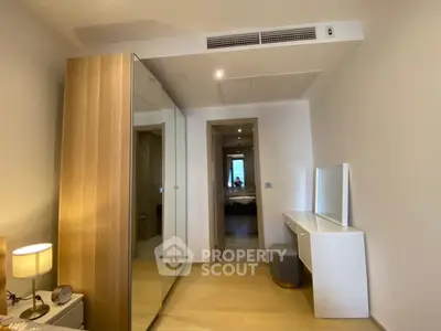 Modern bedroom with mirrored wardrobe and sleek vanity in a minimalist design.