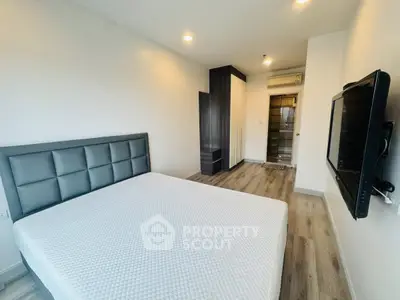 Modern bedroom with sleek design, featuring a stylish bed and wall-mounted TV, perfect for urban living.