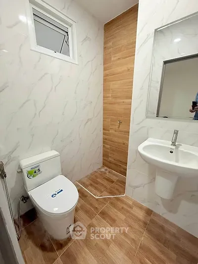 Modern bathroom with sleek design, featuring a toilet, sink, and stylish tile flooring.