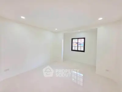 Spacious empty room with bright lighting and a window, ideal for customization.