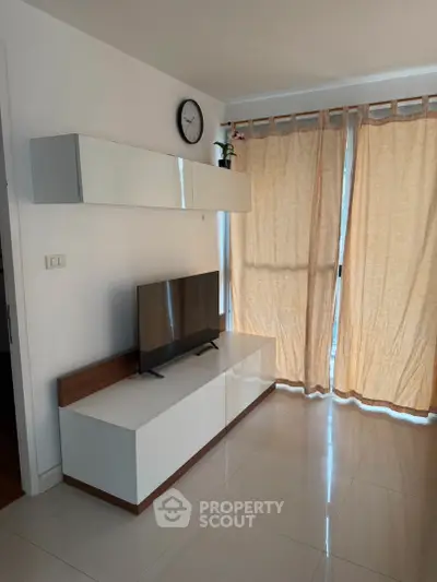 Modern living room with sleek TV stand and wall-mounted shelves, featuring natural light through elegant curtains.