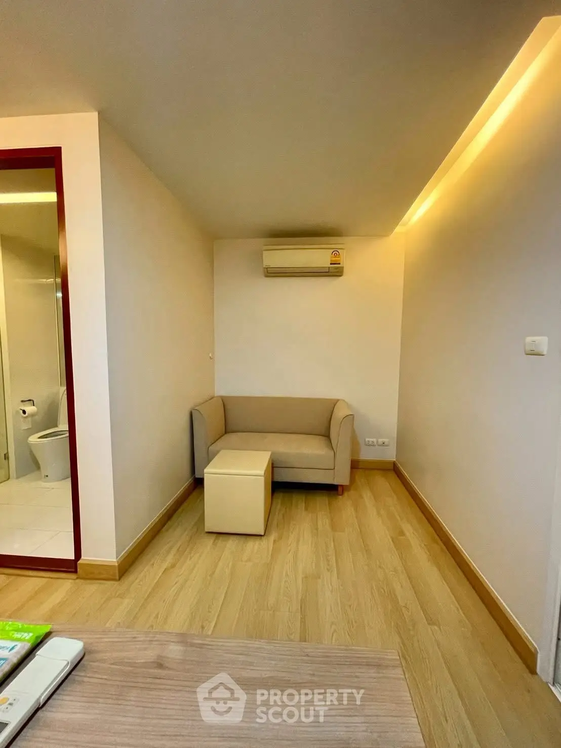 Cozy living room with modern sofa and air conditioning, featuring warm lighting and wooden flooring.
