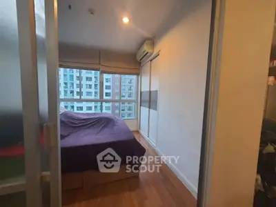 Cozy bedroom with large window and wooden flooring in modern apartment