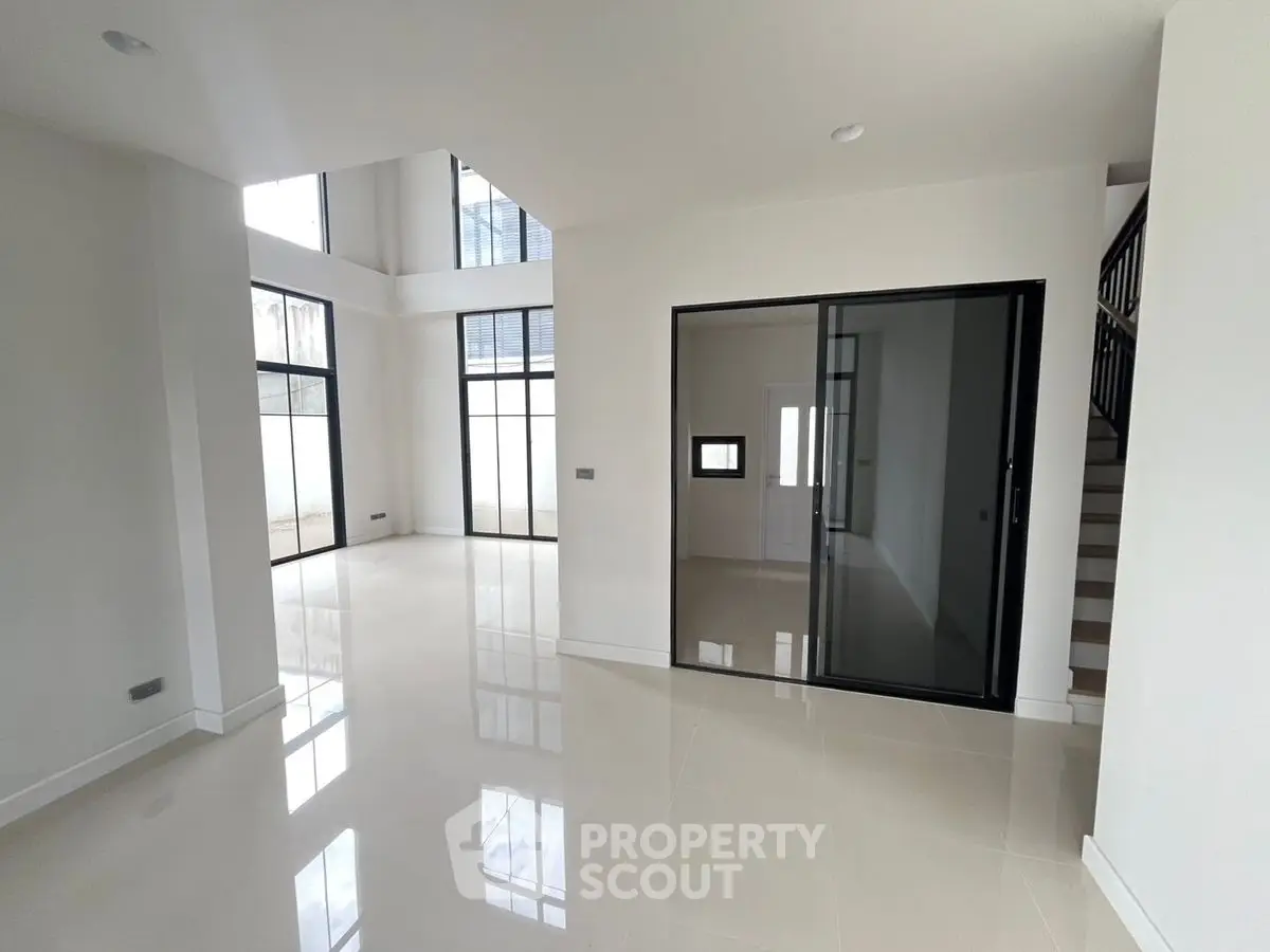 Spacious modern living room with high ceilings and large windows in a contemporary home.